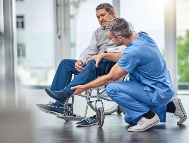 Male Doctor in scrubs helping a man in a wheelchair
